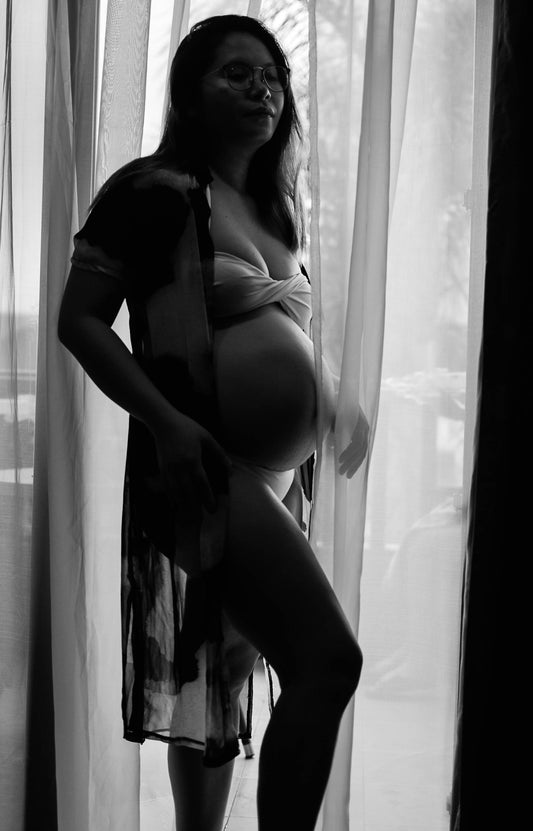 a pregnant woman standing in front of a window