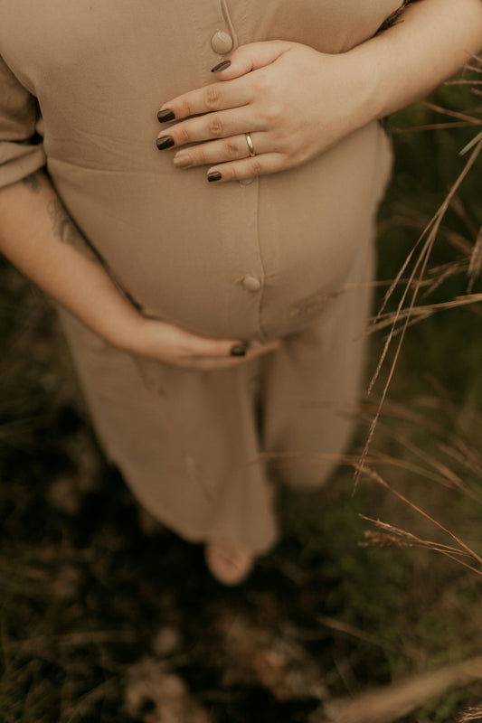Pregnant woman cradling her belly in a field.